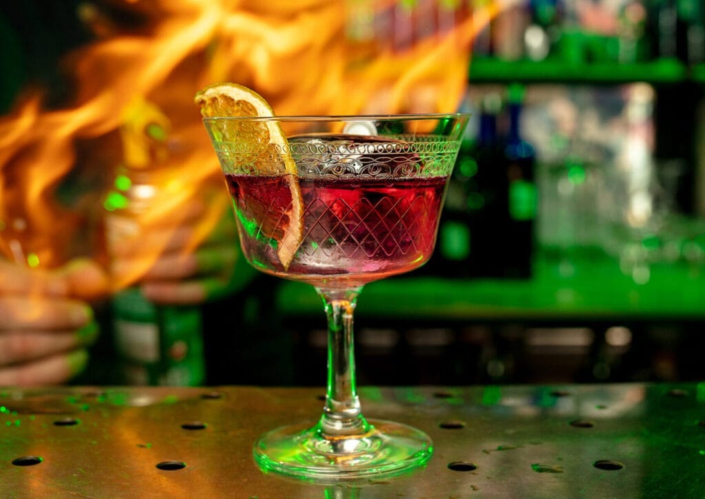 signature cocktails and craft beers - Close-up of a vibrant cocktail illuminated by neon lights, with flames in the backgroun